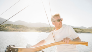Hombre con gafas de sol navegando en un velero durante el atardecer